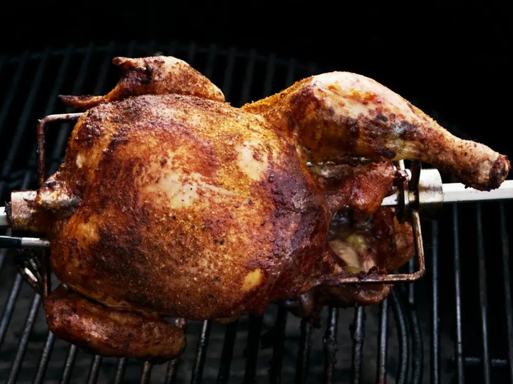 Whole chicken roasting over charcoal